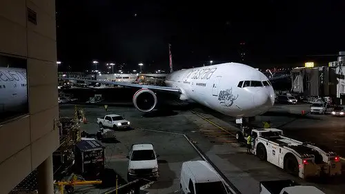 Boeing 777 parked at the airport gate at night.